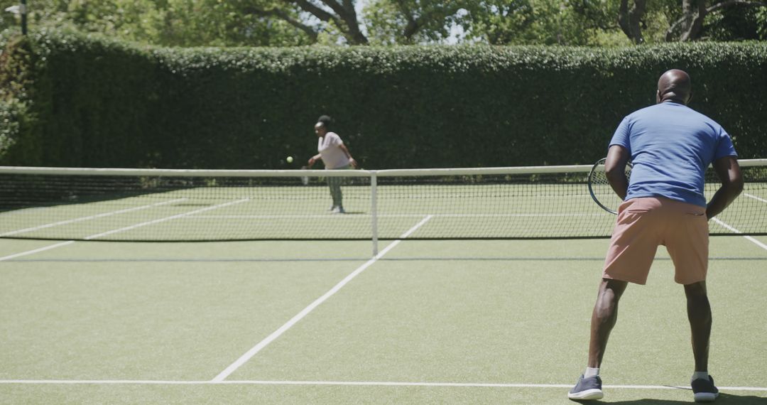 Two Men Playing Tennis Outdoors on Sunny Day - Free Images, Stock Photos and Pictures on Pikwizard.com