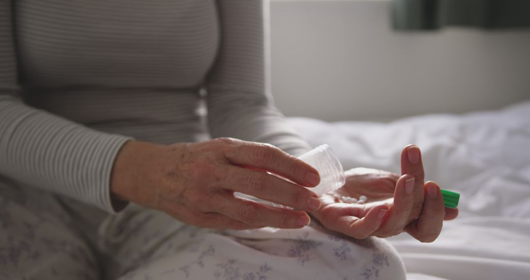 Older woman holding medication bottle preparing to take pills - Free Images, Stock Photos and Pictures on Pikwizard.com