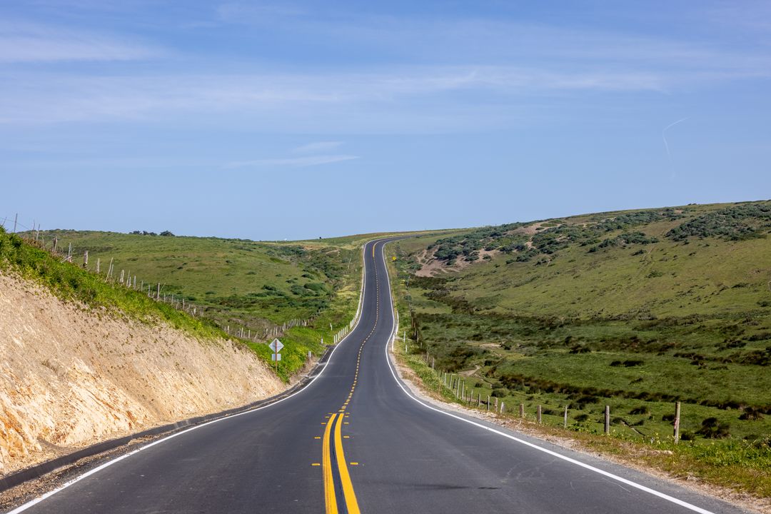Long Empty Road Winding Through Green Hills