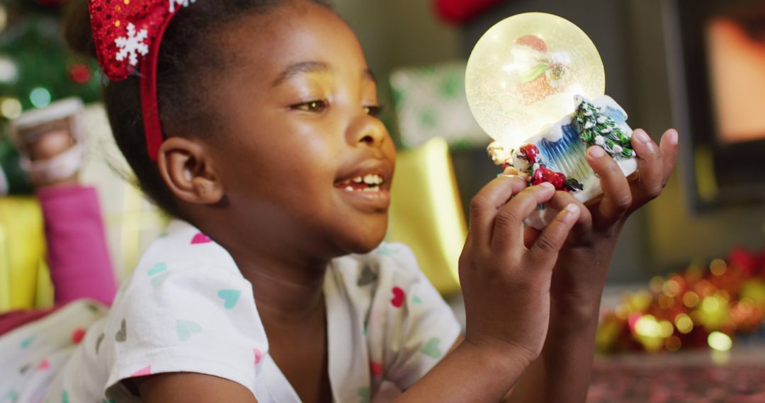 Happy african american girl playing with snow globe - Free Images, Stock Photos and Pictures on Pikwizard.com