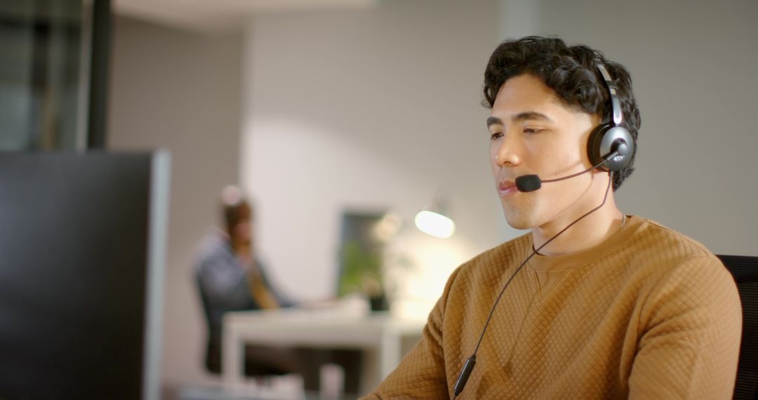 Customer Support Agent Wearing Headset Working at Computer in Modern Open Office
