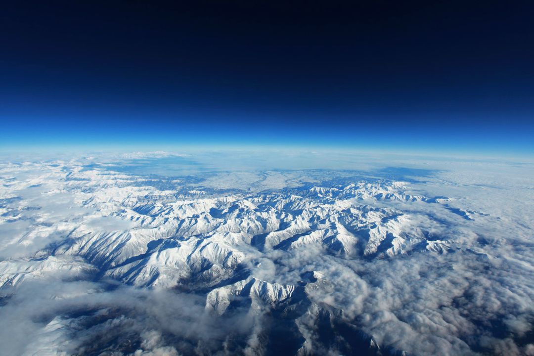 Aerial View of Snow-Covered Mountain Range Under Clear Blue Sky - Free Images, Stock Photos and Pictures on Pikwizard.com