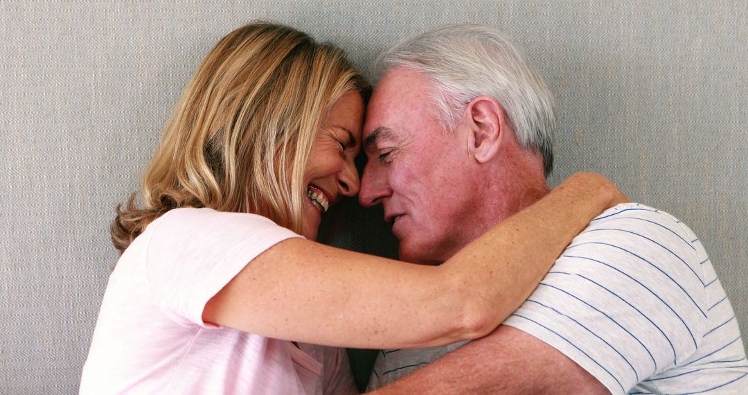 Happy Senior Couple Embracing and Laughing Together Indoors - Free Images, Stock Photos and Pictures on Pikwizard.com