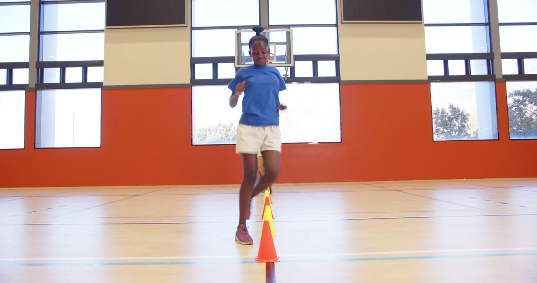 Energetic Girl in Gym Practicing Agility Drills with Colorful Cones