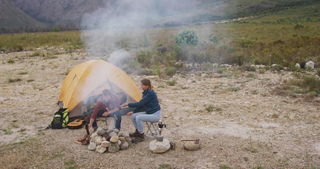 Couple Cooking Over Campfire Near Tent in Mountainous Landscape - Free Images, Stock Photos and Pictures on Pikwizard.com