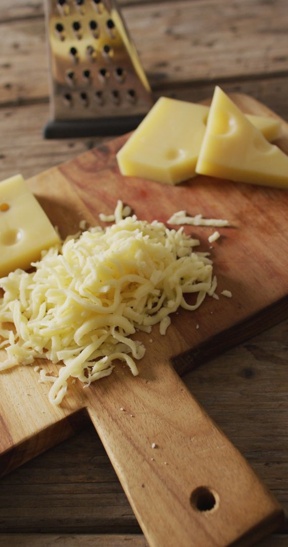 Grated Swiss Cheese and Cheese Slices on Rustic Wooden Board