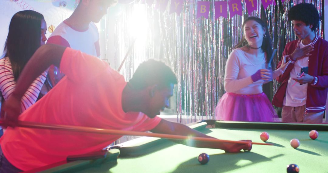 Multicultural Friends Playing Pool at Lively Birthday Party with Neon Fringe Backdrop