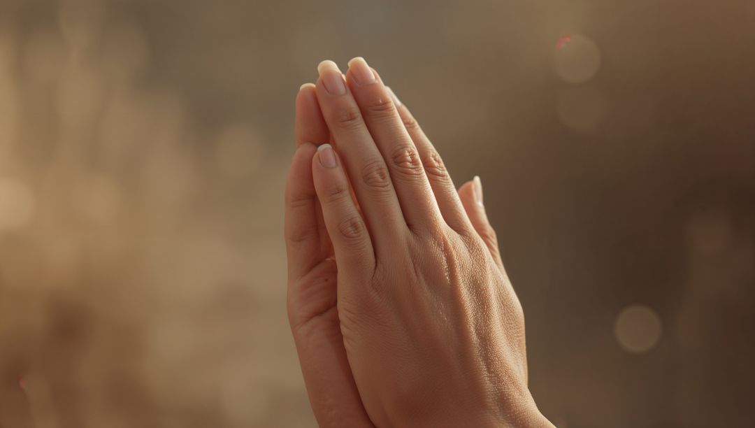 Hands in Prayer Gesture with Warm Bokeh Background