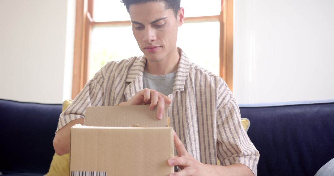 Man Opening Cardboard Box at Home, Discovering Surprise