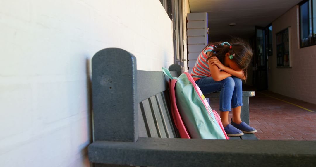 Upset Schoolgirl Sitting Alone on Bench in School Corridor