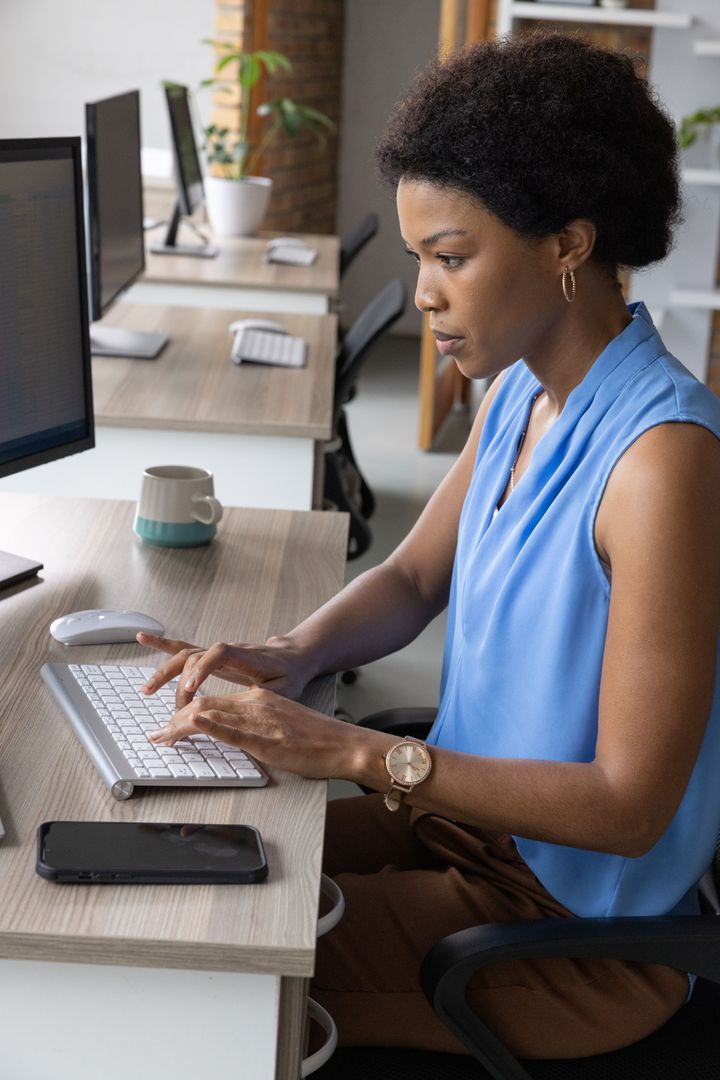 Focused Professional Woman Typing at Shared Workspace