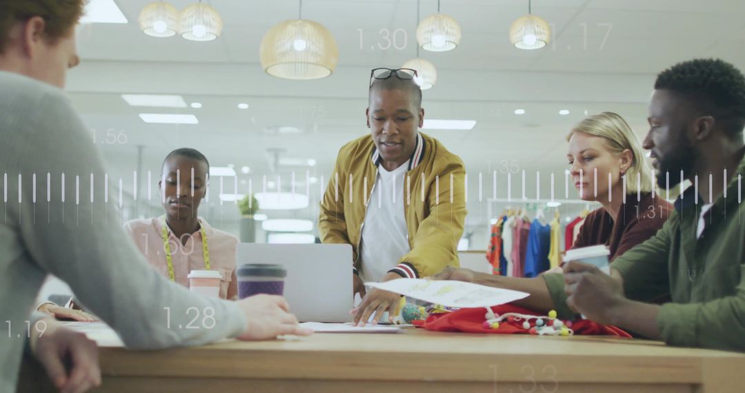 Creative team collaborating over laptop with fabric swatches in fashion design studio