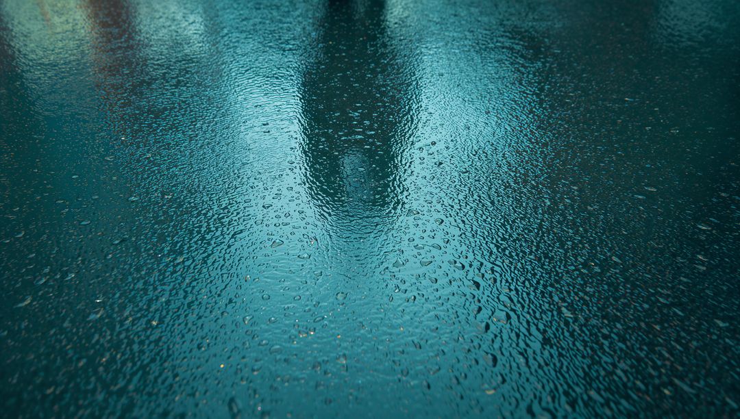 Raindrops on Wet Asphalt Creating Reflective Puddles