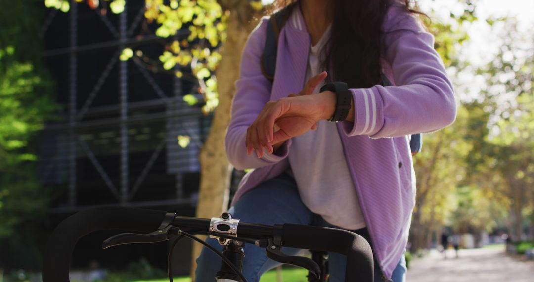 Female Cyclist Checking Smartwatch for Time and Fitness Stats on Urban Path - Free Images, Stock Photos and Pictures on Pikwizard.com