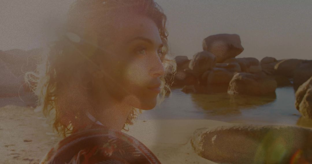 Woman Contemplating on Sunset Beach with Boulders and Lens Flare