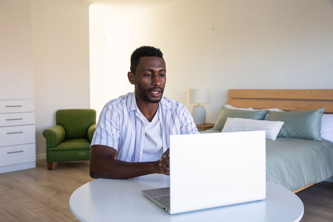 Man Working Remotely with Laptop in Cozy Bedroom Workspace