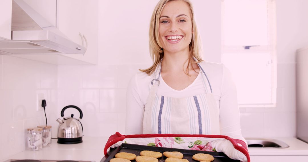 Smiling Woman Presenting Freshly Baked Cookies in Modern Kitchen