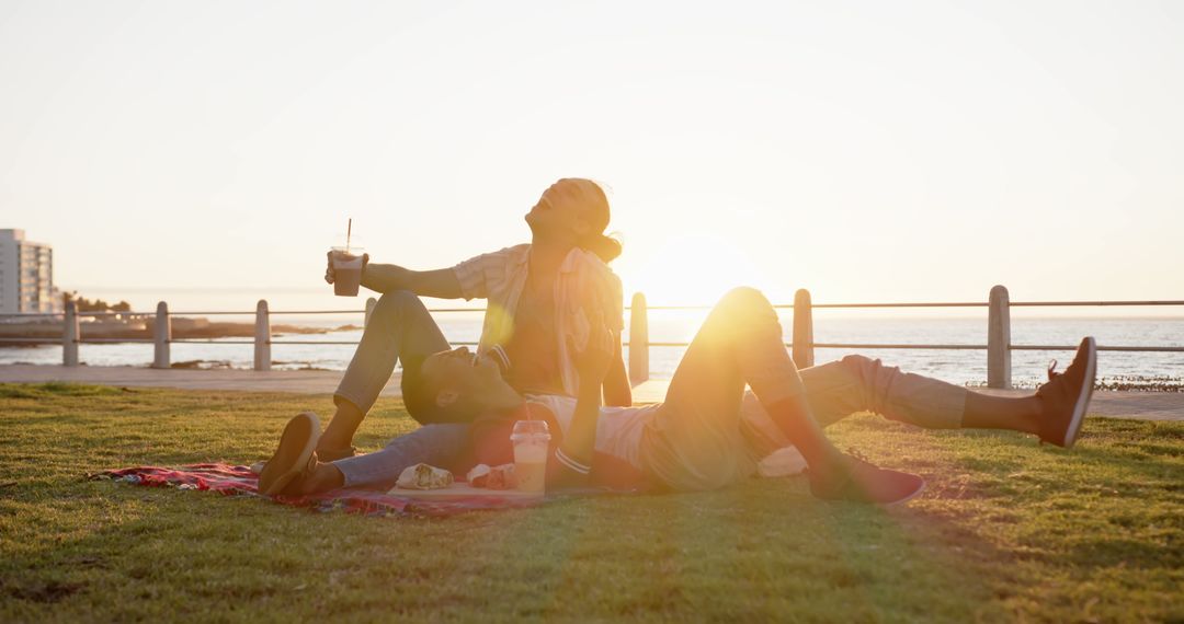 Couple Enjoying Warm Sunset and Beverages on Seaside Picnic - Free Images, Stock Photos and Pictures on Pikwizard.com