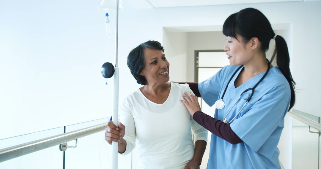 Nurse Assisting Elderly Patient with IV Drip in Bright Hospital Hallway - Free Images, Stock Photos and Pictures on Pikwizard.com