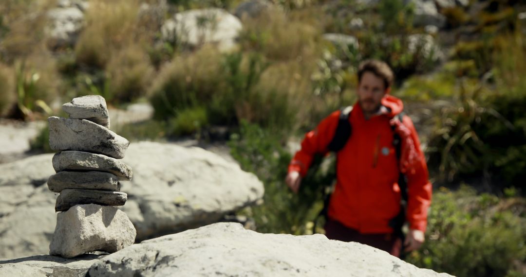 Hiker Wearing Red Jacket Walking in Mountain Landscape Focuses on Stone Cairn - Free Images, Stock Photos and Pictures on Pikwizard.com