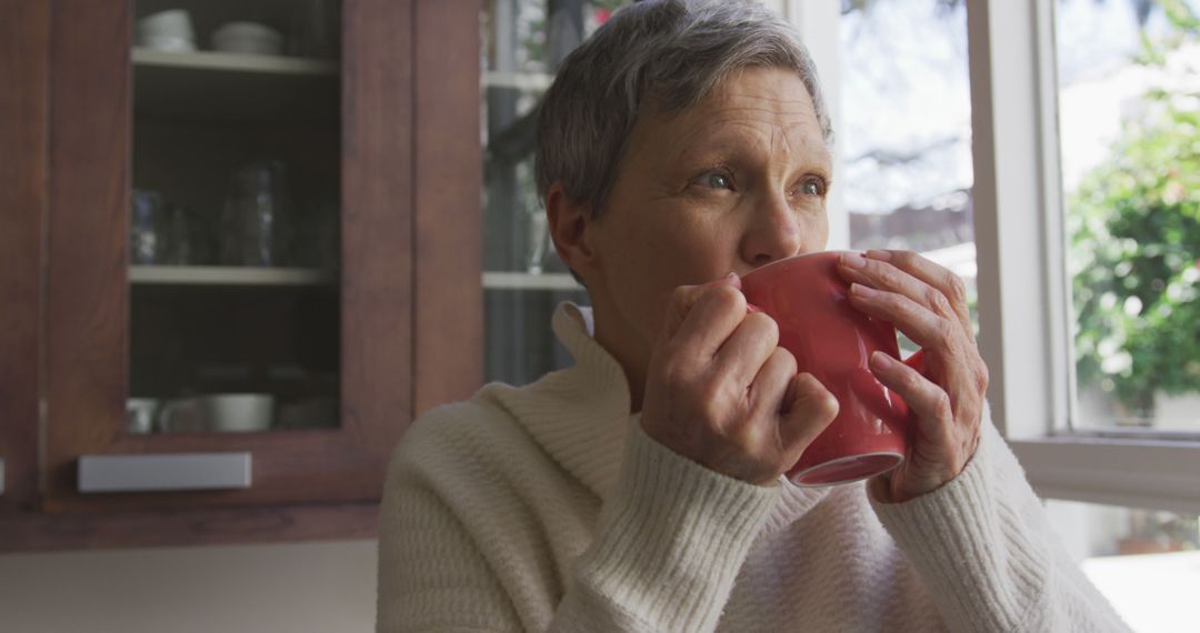 Senior Woman Drinking Hot Beverage by Window at Home - Free Images, Stock Photos and Pictures on Pikwizard.com