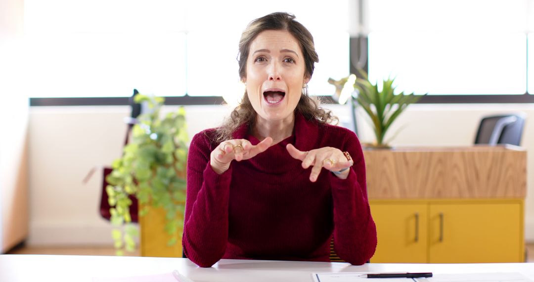 Expressive Woman in Red Sweater Gesturing While Speaking in Office - Free Images, Stock Photos and Pictures on Pikwizard.com