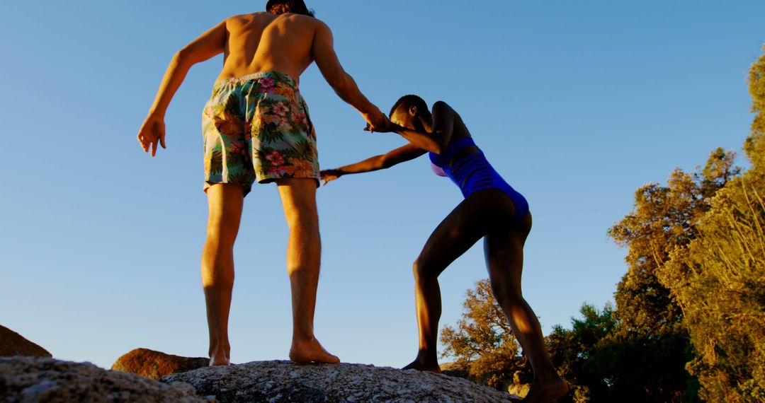 Diverse Couple Climbing Rocks on Sunny Beach Adventure - Free Images, Stock Photos and Pictures on Pikwizard.com