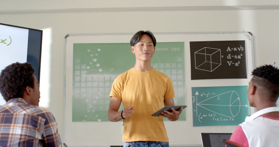 Educator Holding Tablet Presenting to Students in Classroom