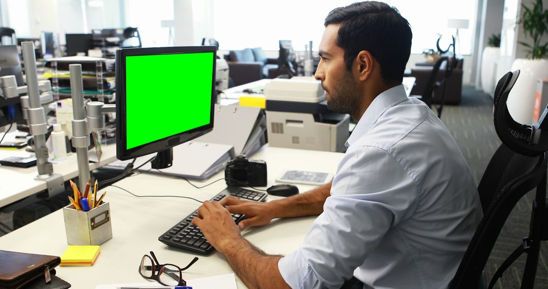 Young Professional Working at Office Desk with Green Screen Monitor - Free Images, Stock Photos and Pictures on Pikwizard.com