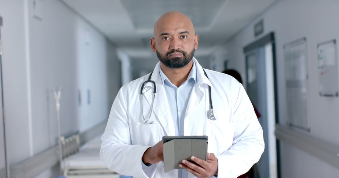 Confident Male Doctor with Tablet in Hospital Corridor - Free Images, Stock Photos and Pictures on Pikwizard.com