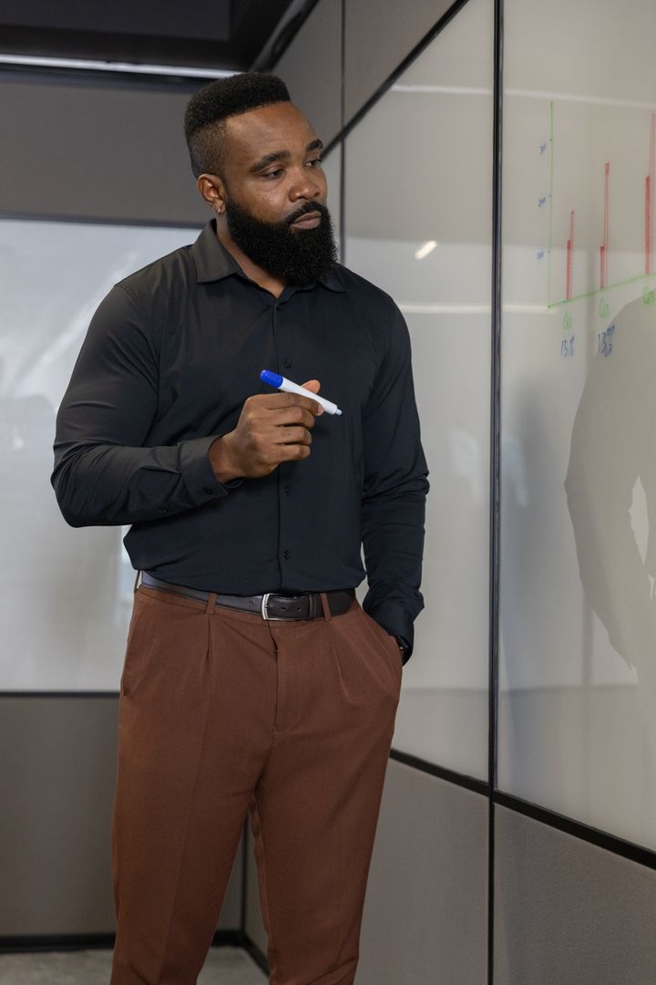 Businessman Analyzing Whiteboard Data in Modern Office Environment