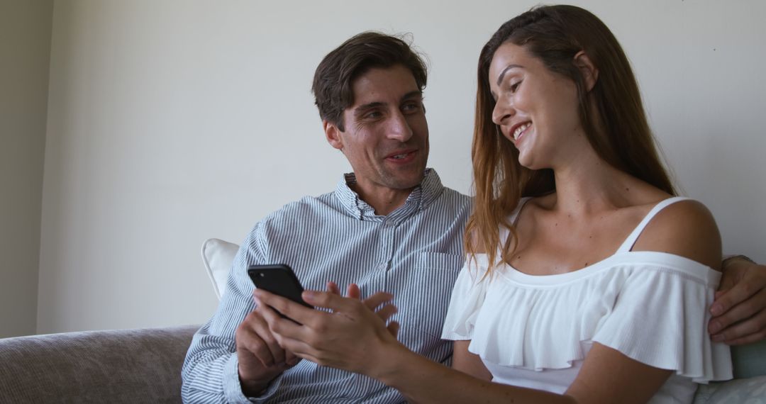 Couple Smiling Together Using Smartphone on Couch