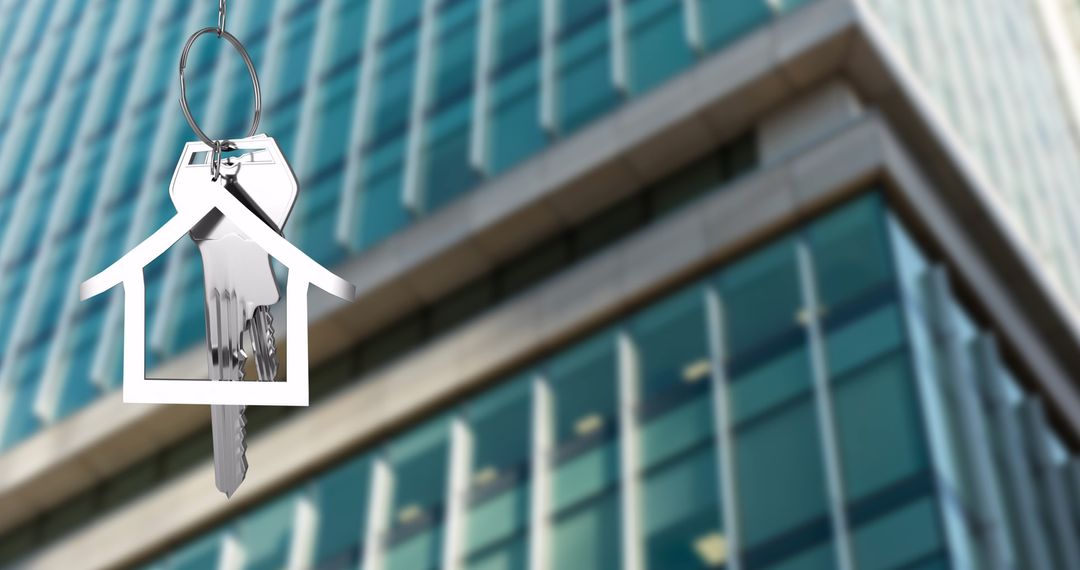 Silver House Key on Keyring in Front of Modern Office Building