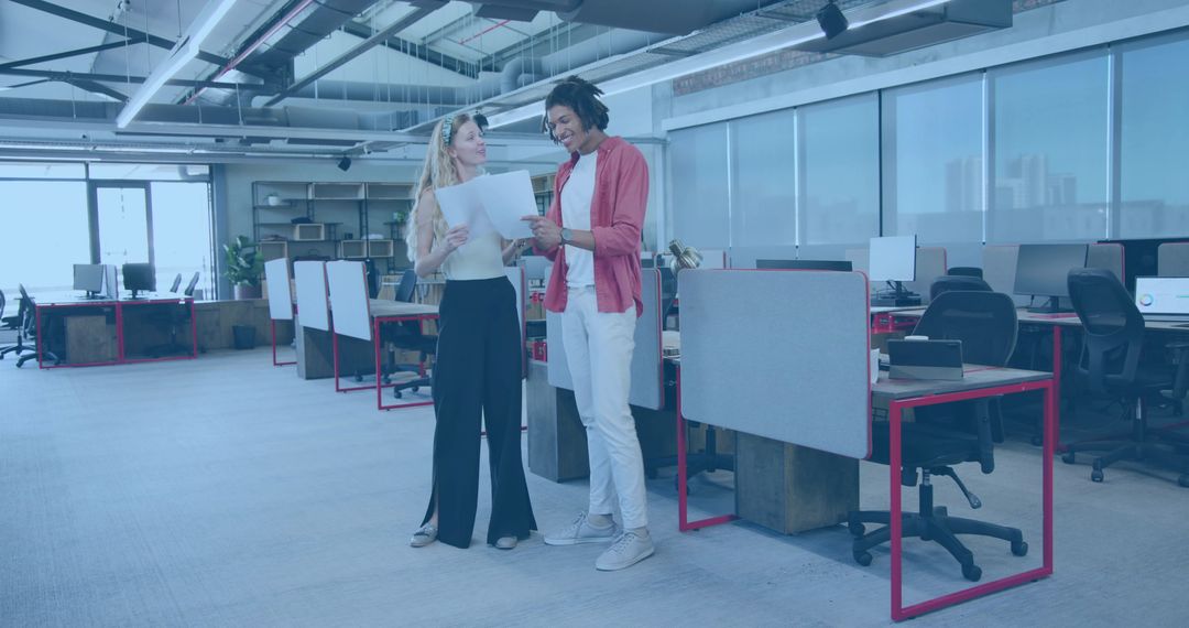 Colleagues reviewing documents in modern open-plan office, teamwork and collaboration