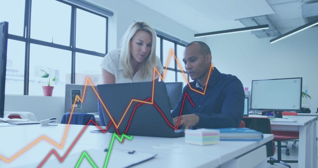 Colleagues Analyzing Data with Graphs in Modern Office