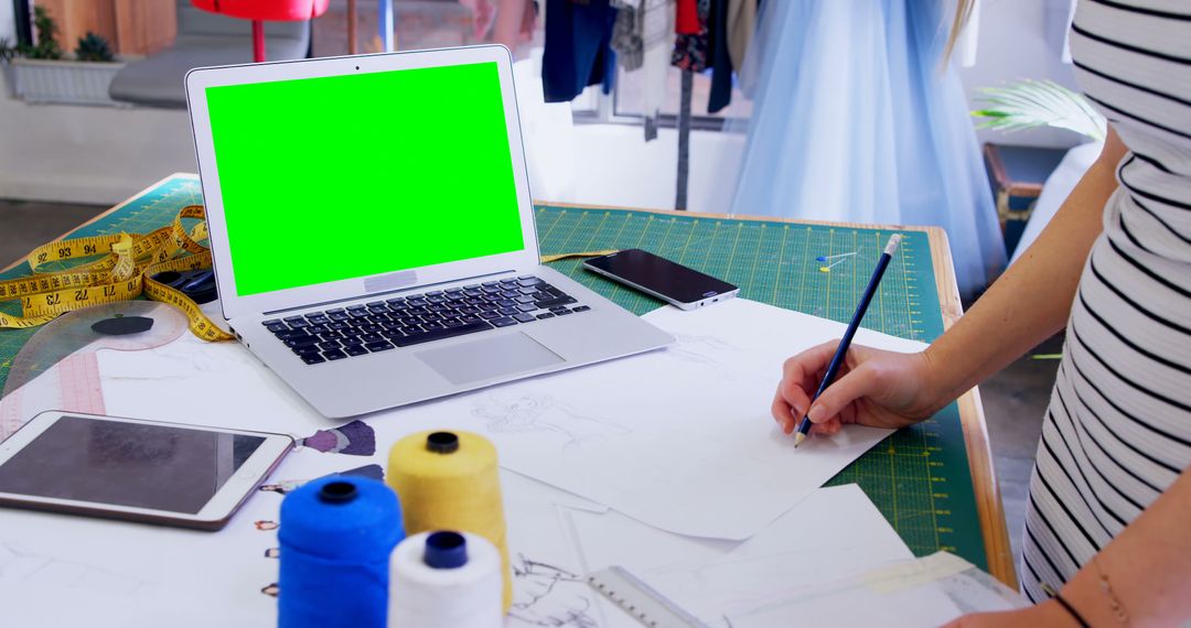 Fashion Designer Sketching on Desk with Open Laptop with Green Screen - Free Images, Stock Photos and Pictures on Pikwizard.com