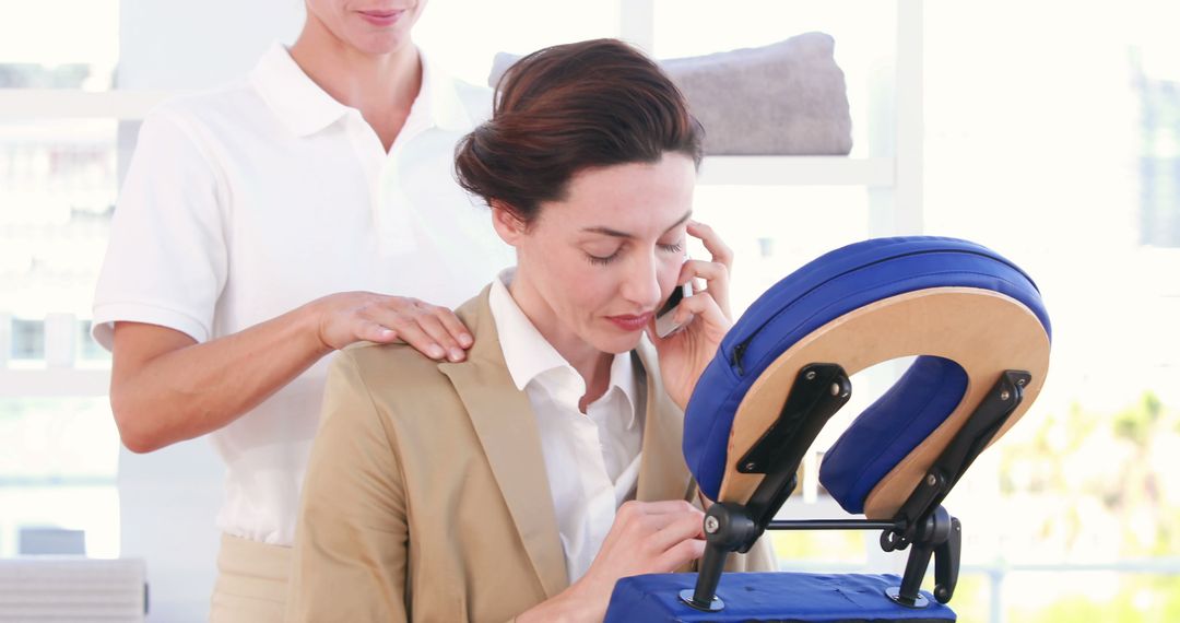 Businesswoman Receiving Chair Massage While Talking on Phone - Free Images, Stock Photos and Pictures on Pikwizard.com