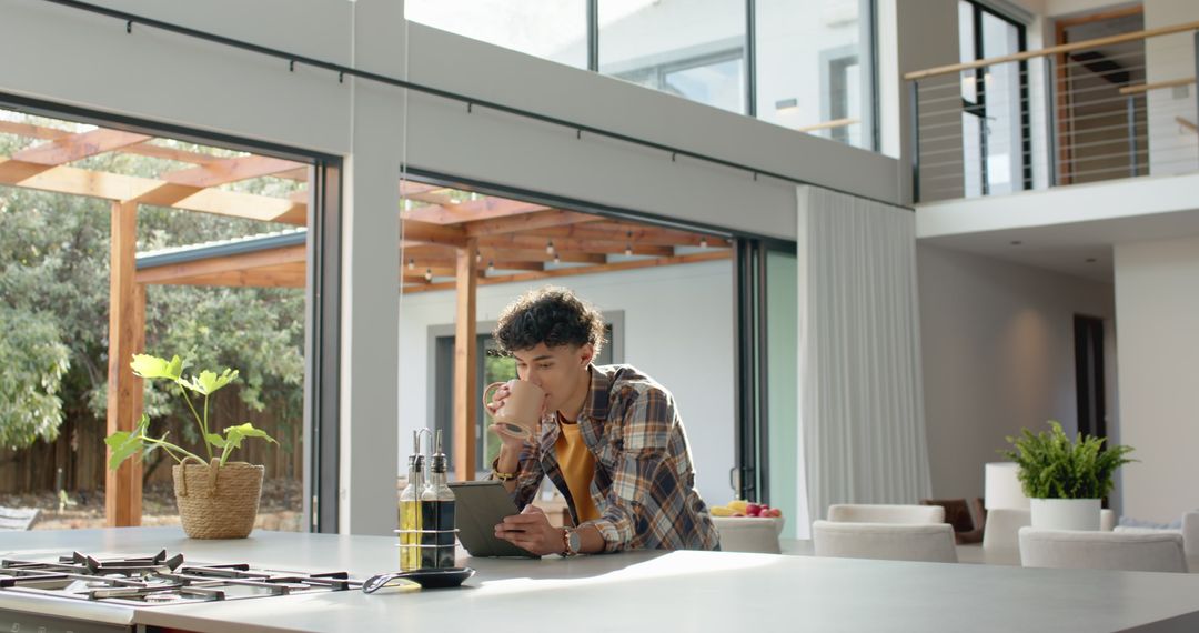 Man Enjoying Beverage While Using Tablet in Contemporary Kitchen