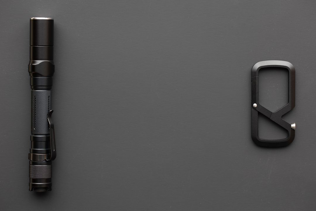 Black Flashlight and Carabiner on Dark Background