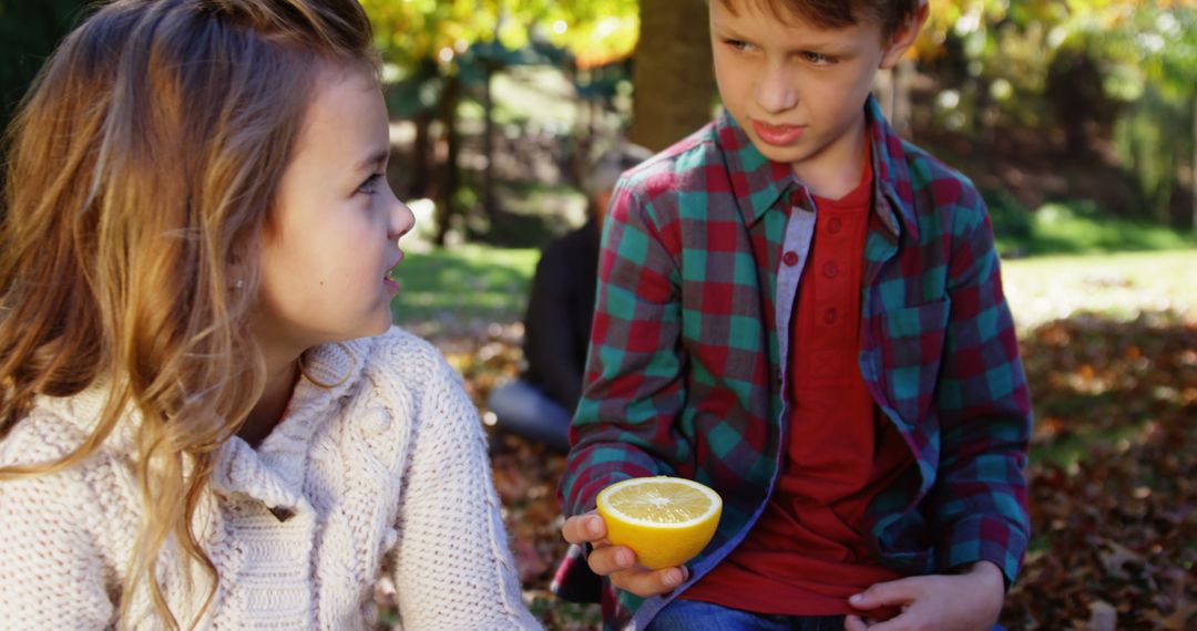 Children Outdoors Sharing Fresh Lemon in Autumn Park - Free Images, Stock Photos and Pictures on Pikwizard.com