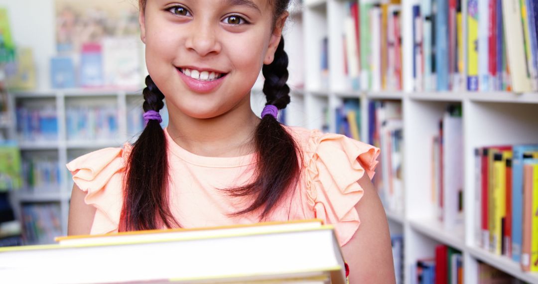 Smiling Schoolgirl Holding Books in Library Setting - Free Images, Stock Photos and Pictures on Pikwizard.com