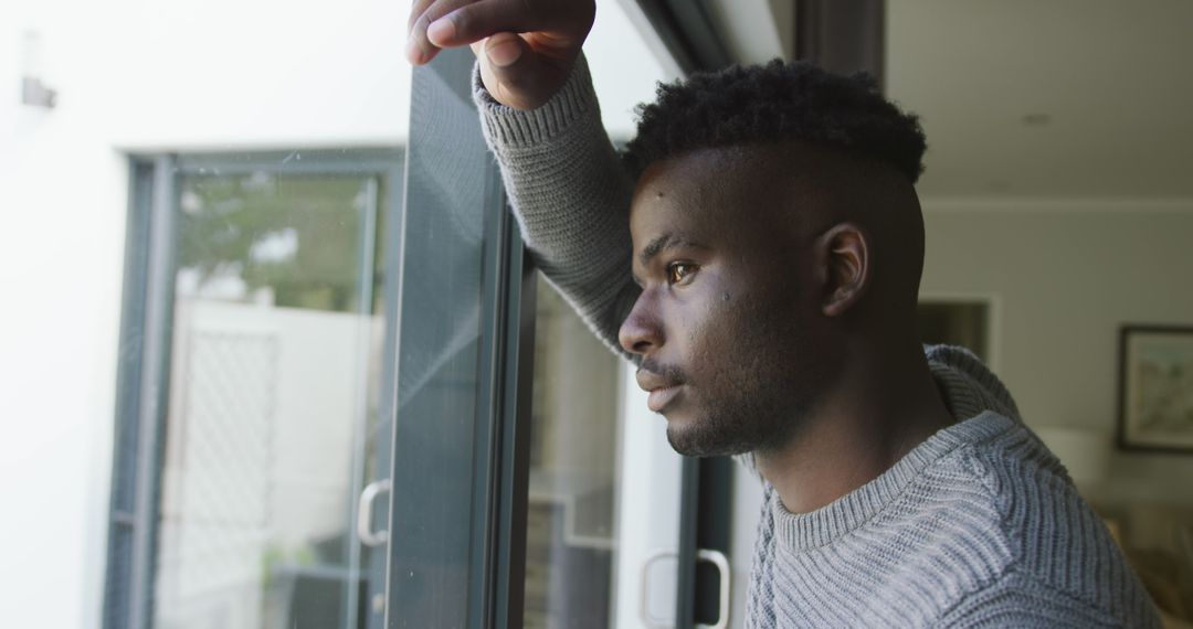 Image of sad african american man looking outside window - Free Images, Stock Photos and Pictures on Pikwizard.com