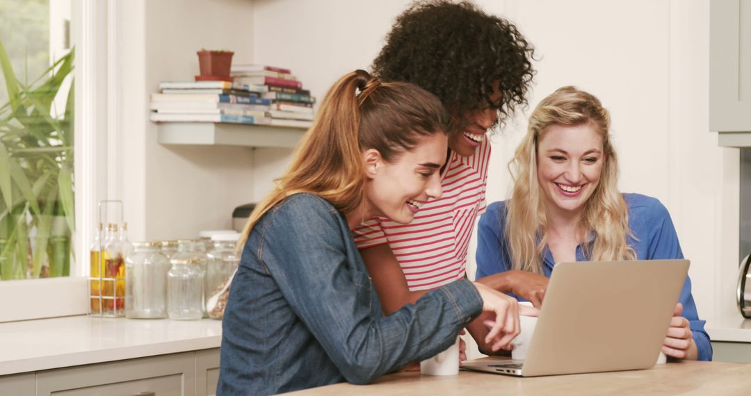 Three Women Smiling and Laughing While Looking at Laptop in Kitchen - Free Images, Stock Photos and Pictures on Pikwizard.com