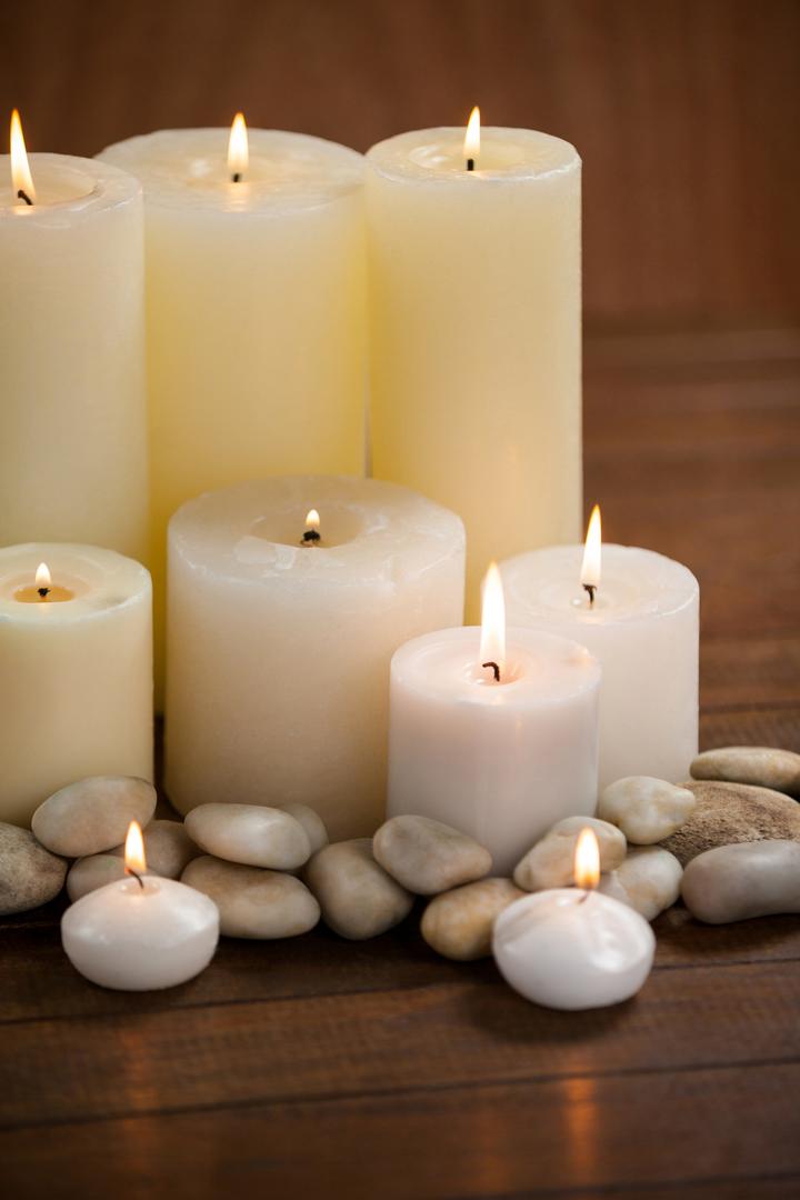 Close- up of white candles and pebbles stone on wood - Free Images, Stock Photos and Pictures on Pikwizard.com