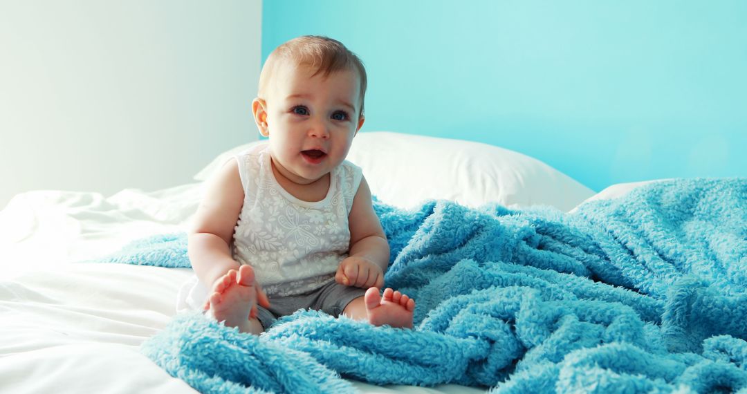 Adorable Baby Sitting on Bed with Blue Blanket and White Sheets - Free Images, Stock Photos and Pictures on Pikwizard.com