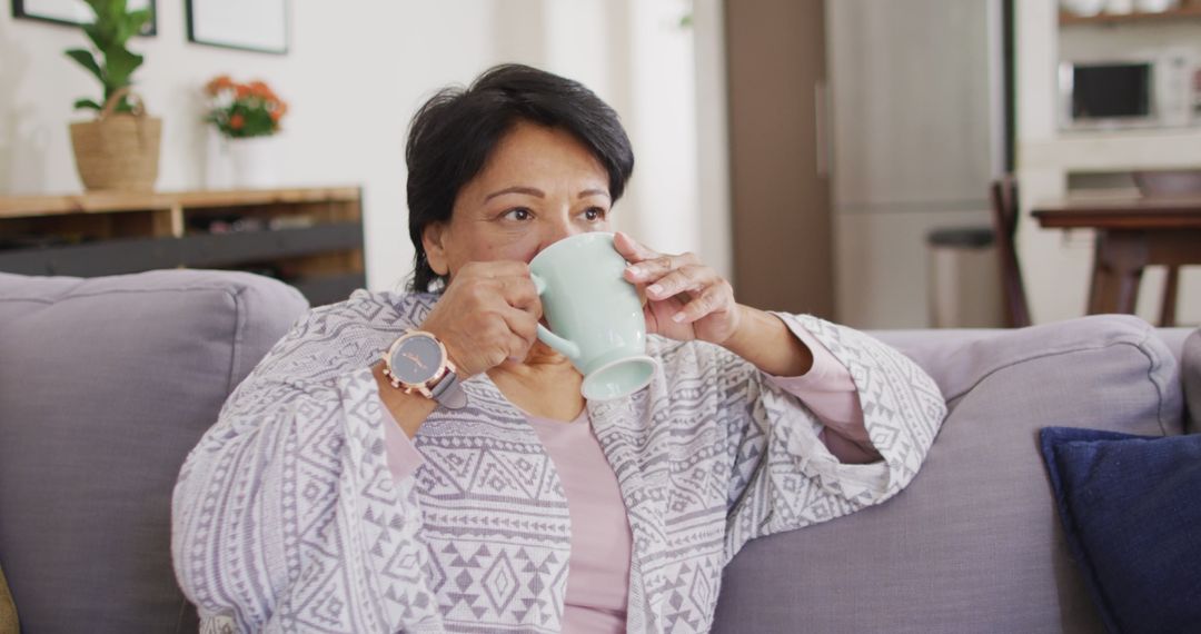 Elderly woman drinking coffee while relaxing on couch at home - Free Images, Stock Photos and Pictures on Pikwizard.com