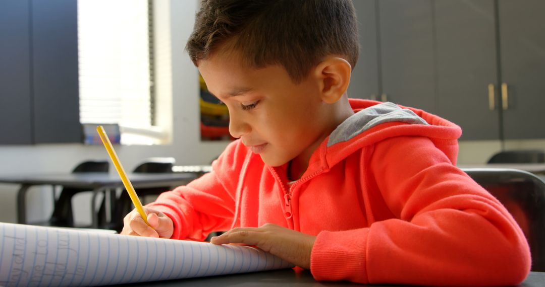 Young Boy Studying Diligently at School Desk with Notebook