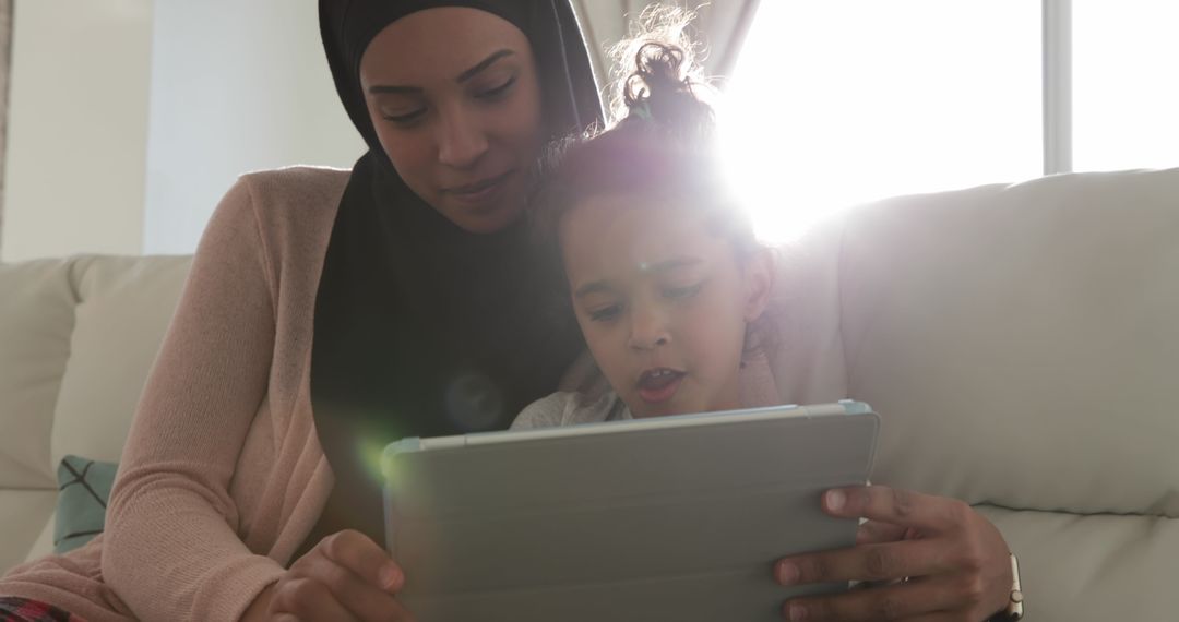 Mother and Daughter Using Tablet Together on Cozy Sofa