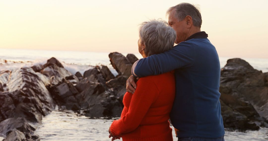 Senior Couple Embracing by Rocky Seaside at Sunset - Free Images, Stock Photos and Pictures on Pikwizard.com