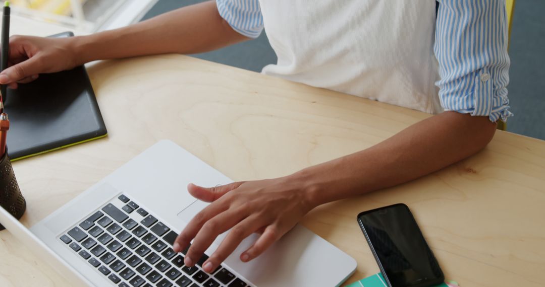 Person Working on Laptop at Wooden Desk